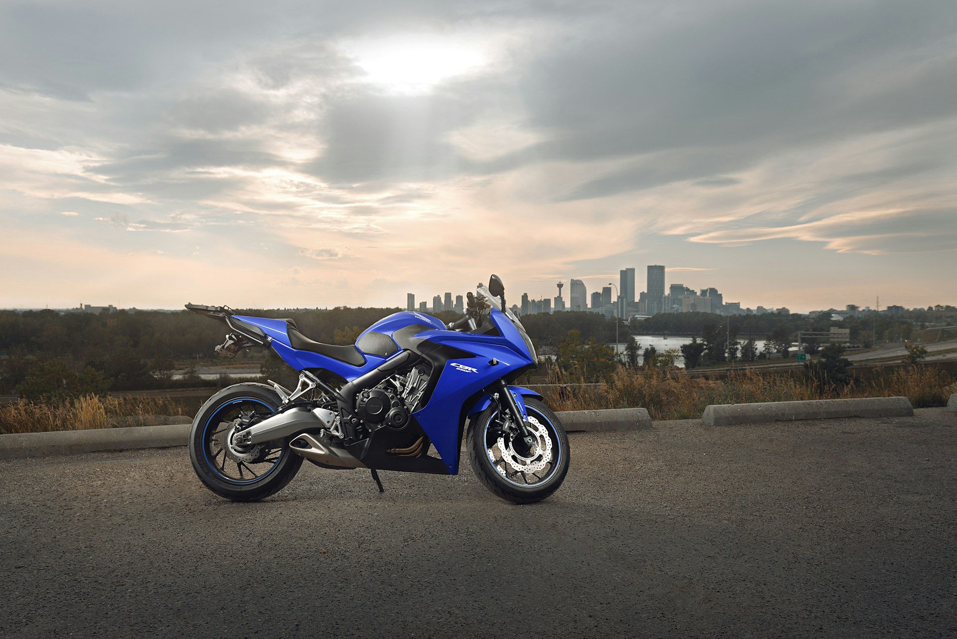 a blue motorcycle parked with the city of Calgary behind