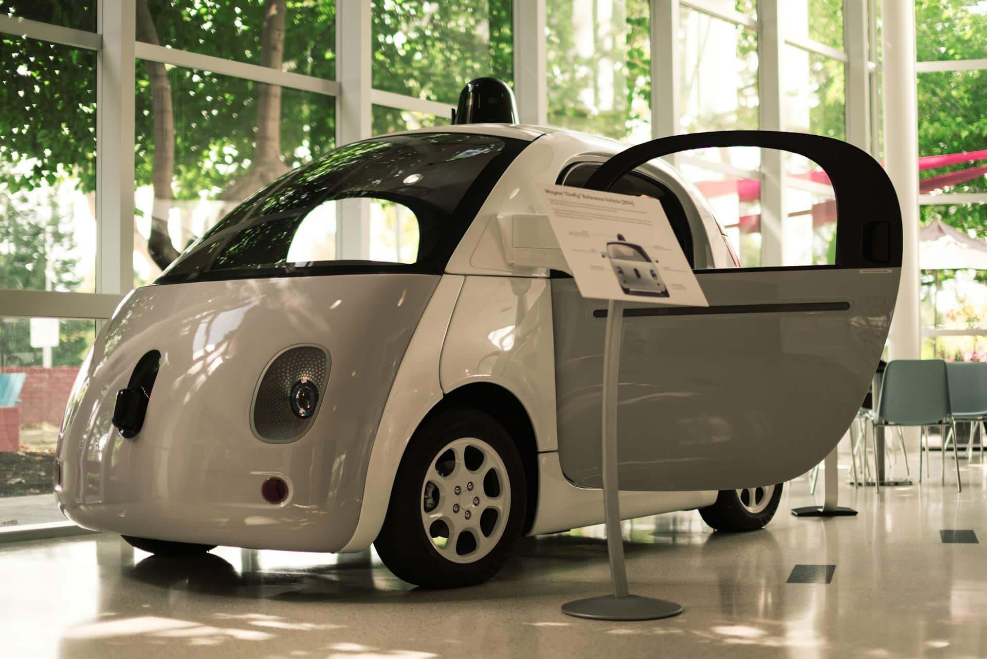 An exhibit of a white self-driving car in a technology museum, representing autonomous vehicles/self-driving cars in Alberta