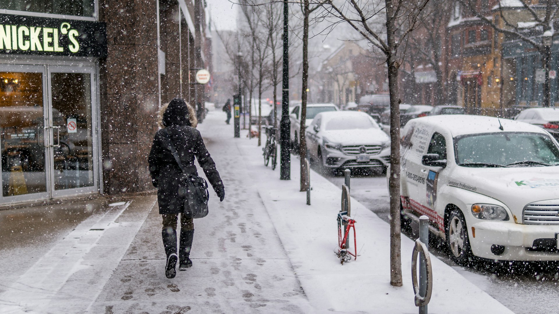 a woman walking on a snowy sidewalk