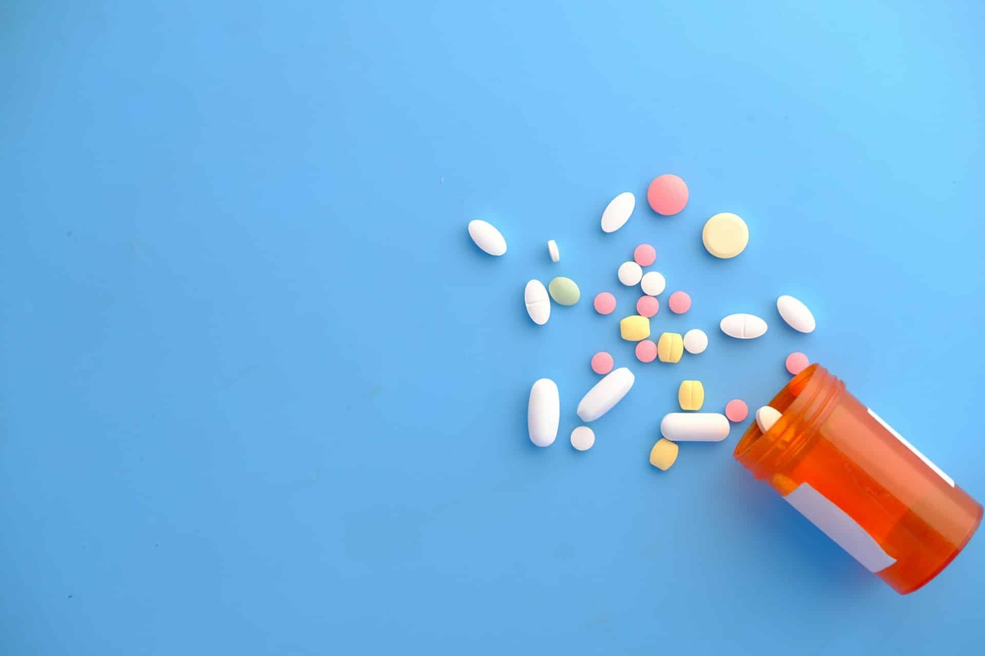 orange and white medication bottle with medication spilled from bottle